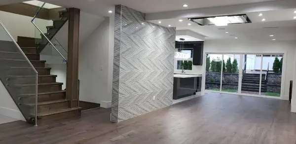 Open living volume with herringbone feature wall and glass stair