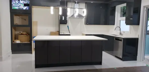 Dark kitchen with island, integrated appliances and pendant lighting