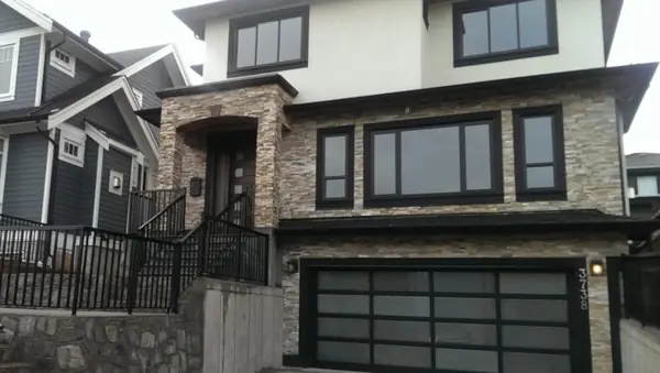 Daytime street elevation with stone cladding and glass garage door